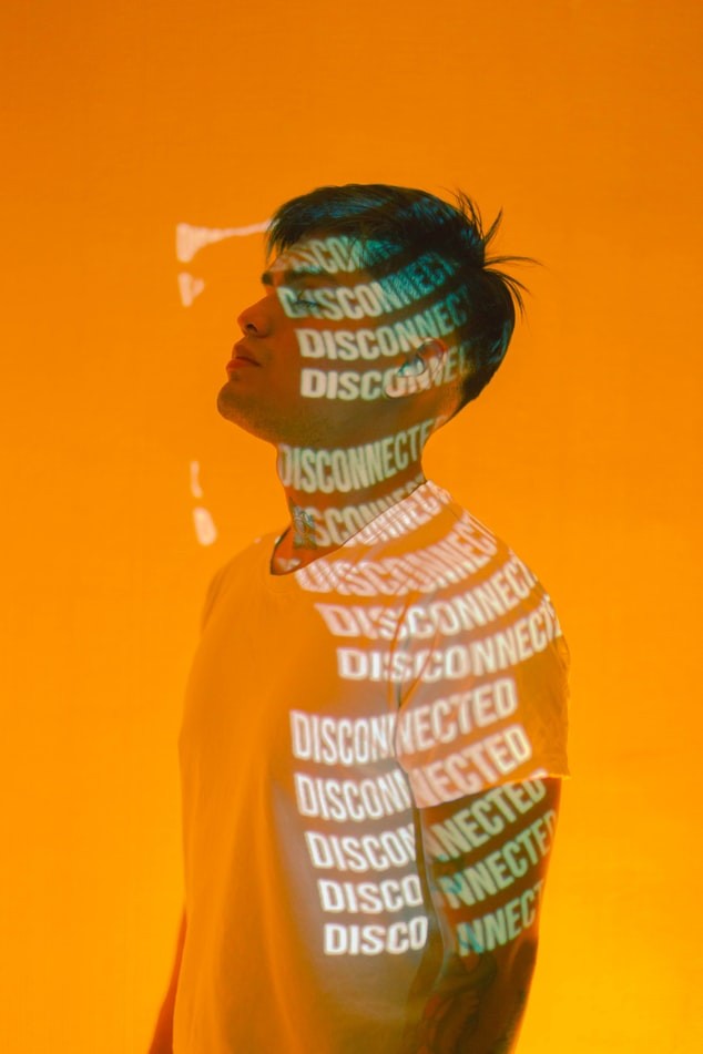 A male figure stands with the word “Disconnected” repeatedly printed on them in a projection